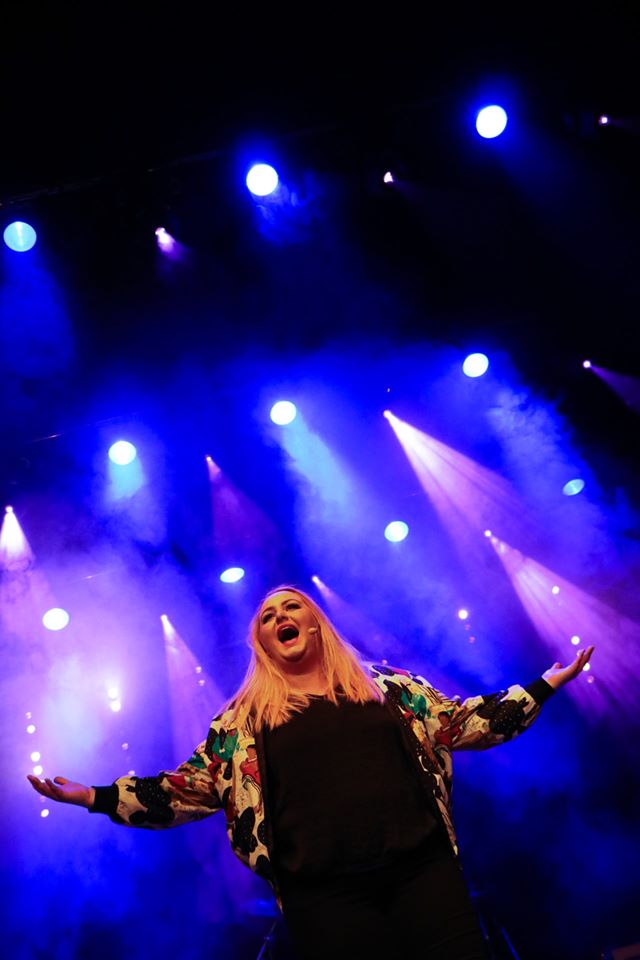 sjungande kvinna med scenbelysning bakom sig