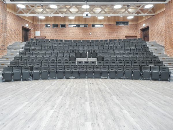 Aulan, grå stolar som står uppställda framför en scen.