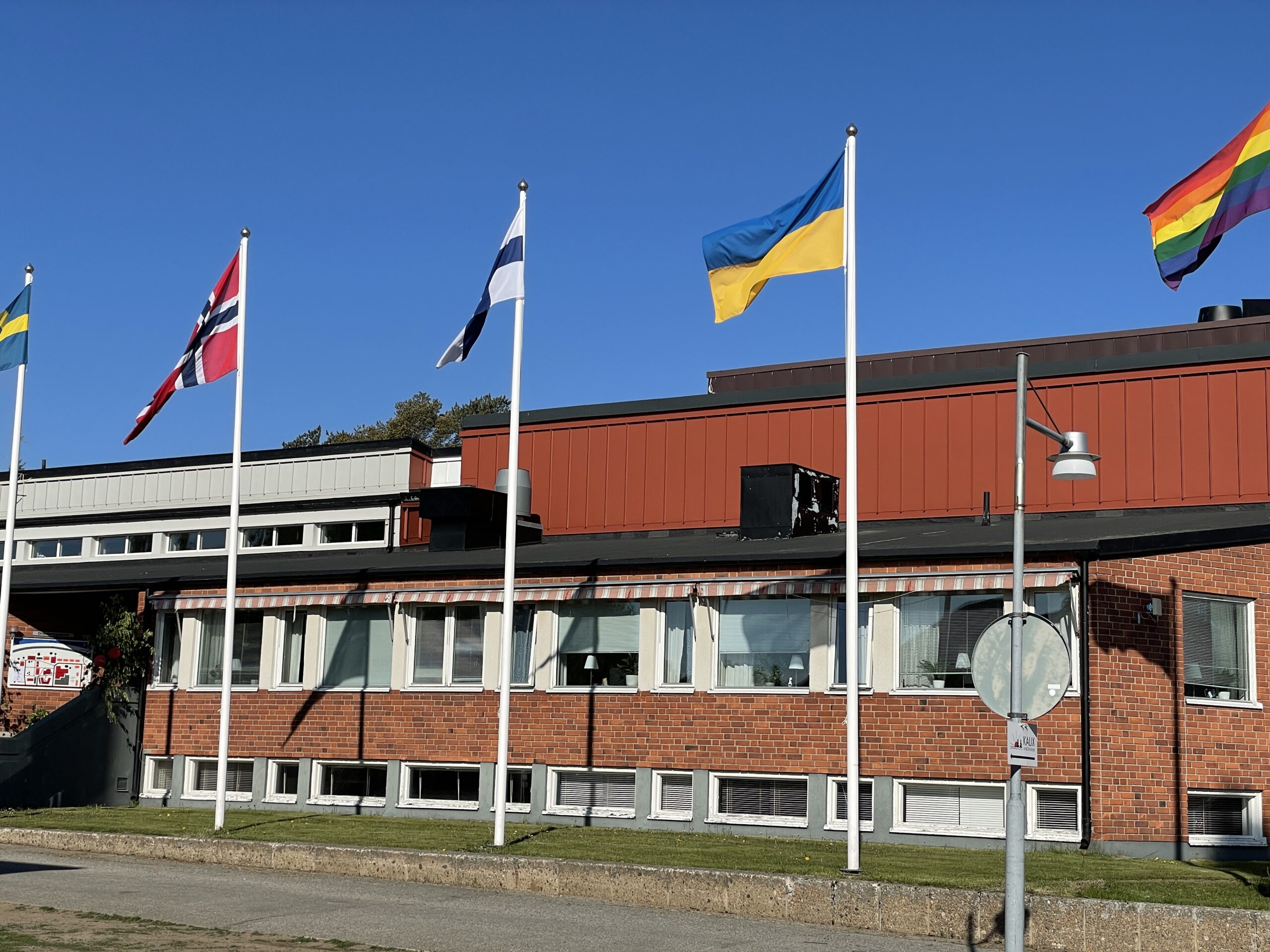 Flaggor framför en röd tegelbyggnad